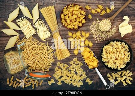 Ampia collezione di varietà di pasta italiana su sfondo rustico in legno. Concetto di cibo di carboidrato. Disposizione piatta, vista dall'alto. Foto Stock