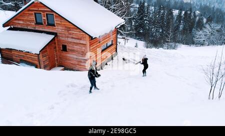 Felice giovane coppia che lancia palle di neve il giorno d'inverno di fronte alla casa di legno. Foto di alta qualità Foto Stock