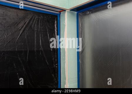 Installazione per tapparelle esterne realizzate in cartongesso all'interno dell'edificio, le finestre sono coperte da un foglio protettivo. Foto Stock