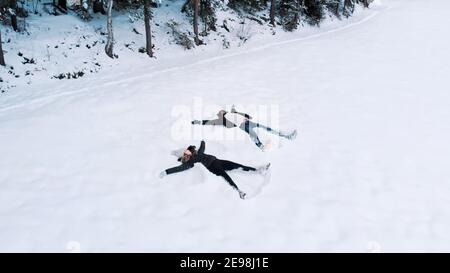 Felice giovane coppia che fa angeli di neve. Angolo alto. Foto di alta qualità Foto Stock