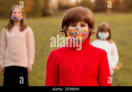 Folla di bambini che camminano in maschere mediche protettive in strada durante l'epidemia di coronavirus. Nuovo concetto di stile di vita di realtà dei bambini con volti coperti. Messa a fuoco selettiva Foto Stock