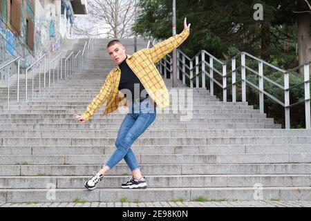 Bel giovane uomo che indossa il make up, balletto danzante sulle scale. Tipo non binario androginoso. Foto Stock