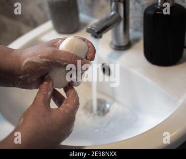 una signora lavando le mani con sapone ad un lavello durante la covid 19 pandemia Foto Stock