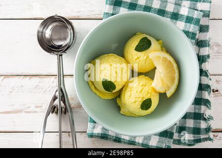 Paletta per gelato al limone decorata con foglie di menta su bianco tavolo di legno Foto Stock