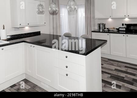 Primo piano dell'elegante cucina, unità in bianco e nero e piano di lavoro, luci e pavimento Foto Stock