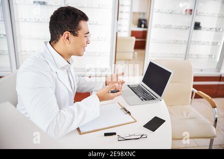 Gioioso oftalmologo pronto a scrivere una prescrizione per gli occhi Foto Stock