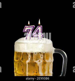 numero 74 candela in tazza di birra per festa di compleanno isolato su nero Foto Stock
