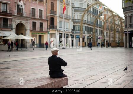 3 febbraio 2021, Malaga, Spagna: Un uomo anziano che indossa una maschera facciale come precauzione contro la diffusione del covid-19 visto poggiare su una panchina in una piazza vuota Plaza de la ConstituciÃ³n, in mezzo al blocco parziale causato dalla pandemia del coronavirus. (Credit Image: © Jesus Merida/SOPA Images via ZUMA Wire) Foto Stock