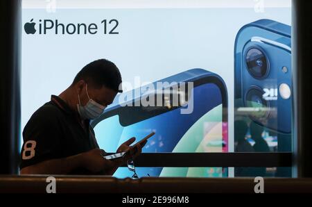 Kuala Lumpur, Malesia. 23 Nov 2020. Un uomo che indossa una maschera facciale passa davanti a un annuncio pubblicitario di iPhone 12. Credit: Faris Hadziq/SOPA Images/ZUMA Wire/Alamy Live News Foto Stock