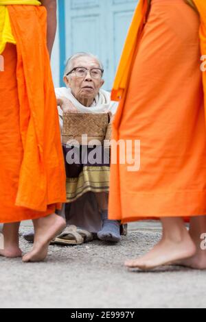 Luang Prabang, Laos Vecchia donna che consegna il riso a Tak Bat o la processione mattutina del monaco. Foto Stock