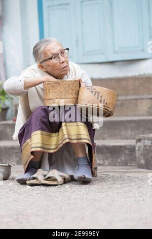 Luang Prabang, Laos Vecchia donna che consegna il riso a Tak Bat o la processione mattutina del monaco. Foto Stock