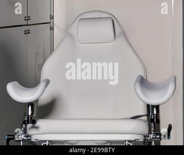 Sedia ginecologica bianca vuota nel moderno centro medico, primo piano, spazio per la copia. Foto Stock