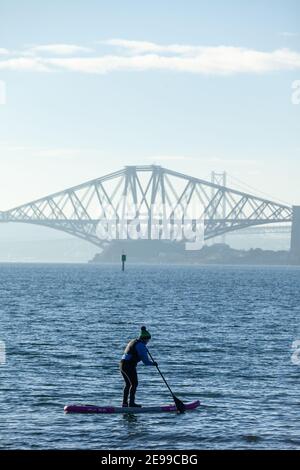 Un paddle boarder godendo del sole invernale sul Firth of Forth vicino al Forth Bridge, al Saint Davids Bay Fife Foto Stock