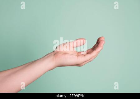 Primo piano della mano maschile con palmo aperto isolato su sfondo blu. Foto Stock