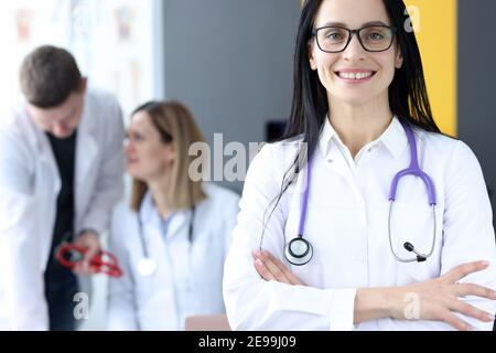 Ritratto di sorridente dottore su sfondo di colleghi Foto Stock