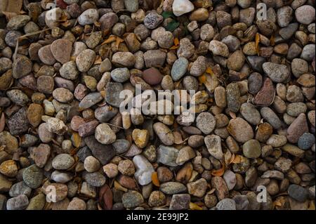 Una macro foto in alto di un letto di ghiaia pieno di rocce di fiume arrotondate. Foto Stock