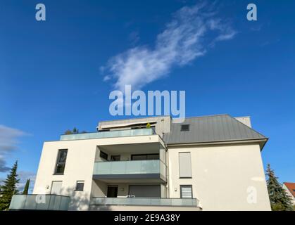 Sfocata vista grandangolare di un moderno edificio di appartamenti con cielo blu sullo sfondo e un edificio a due piani di colore sparso nel cuore della città. Foto Stock