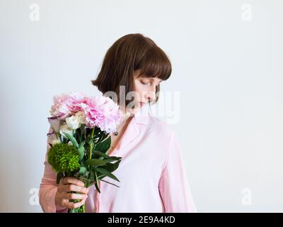 Giovane donna che tiene bel bouquet di peonia pastello Foto Stock