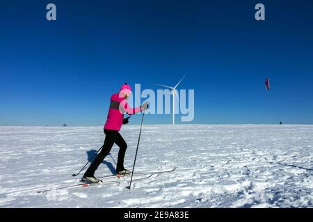 Sport invernali, donna sci di fondo, e uomo di fondo nevicando sotto una turbina eolica Repubblica Ceca montagne pianura Donna sci Foto Stock