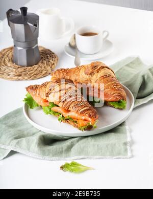 Panino di croissant con salmone e foglie di insalata sul tavolo Foto Stock
