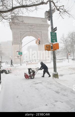New York City USA Washington Square Arch nella neve nel Washington Square Park - persona con spazzaneve Foto Stock