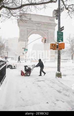 New York City USA Washington Square Arch nella neve nel Washington Square Park - persona con spazzaneve Foto Stock
