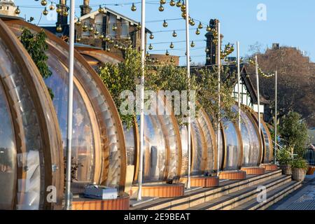 Londra, UK- 15 Dic 2020: Igloos ristorante all'aperto, molte sale di servizio separate in una fila. Gli igloos sul lungofiume del Coppa Club, che si affacciano sul Tower Bridge Foto Stock