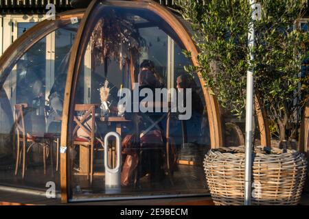 Londra, UK- 15 Dic 2020: Ristorante all'aperto igloo separato sala di servizio in cui cameriera che serve donne musulmane che indossano burkas. Coppa Club's Riverside Foto Stock