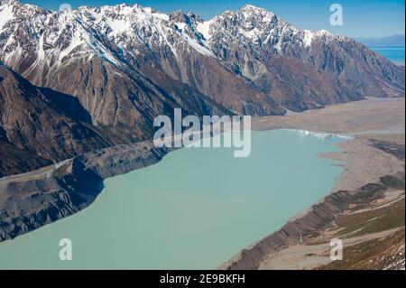 Vista aerea del lago terminale del fiume Tasman nel Parco Nazionale del Monte Cook, Nuova Zelanda. Acque turchesi lattide sul bordo del ghiacciaio circondato dalla neve Foto Stock