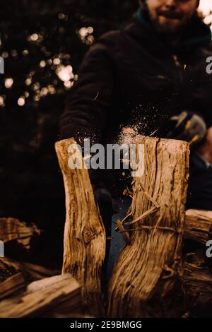 Tagliando tronchi per legna da ardere in azione e primo piano con particelle che volano Foto Stock