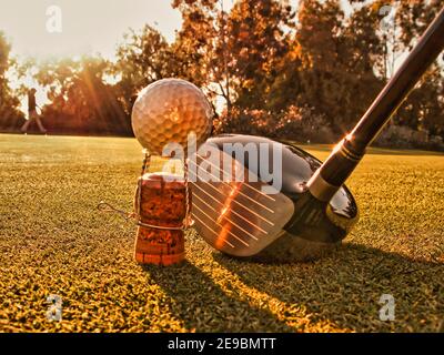 Ancora vita di un randello di golf che affronta una sfera sopra t-shirt in sughero con champagne ta - un divertente colpo per una luce vista dal cuore del golf/tempo libero Foto Stock