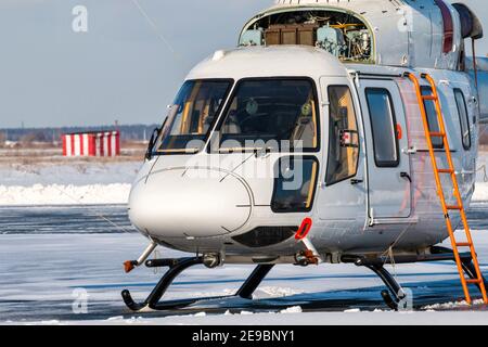 Primo piano di un elicottero bianco con motore aperto acceso il grembiule di un aeroporto invernale Foto Stock
