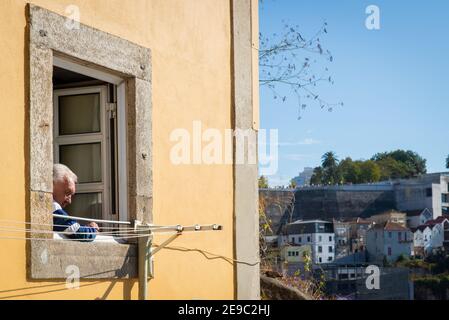 Portogallo, Porto, 06 ottobre 2018: Un anziano guarda fuori dalla finestra della città vecchia. Foto Stock