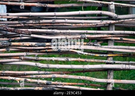 Primo piano recinto fatto di verghe di legno. Recinzione in vimini fatta di ramoscelli. Recinzione rustica naturale fatta di rami. Messa a fuoco morbida Foto Stock