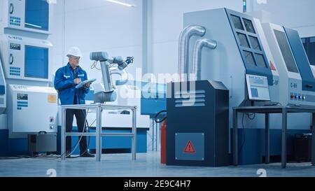 Fabbrica moderna con lavoratori professionisti, ingegneri, responsabili che lavorano su linea di produzione, gestione dell'officina, ottimizzazione. Struttura industriale Foto Stock