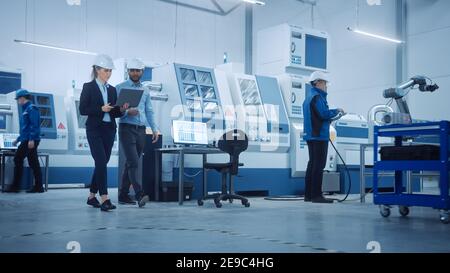 Fabbrica moderna con lavoratori professionisti, ingegneri, responsabili che lavorano su linea di produzione, gestione dell'officina, ottimizzazione. Struttura industriale Foto Stock