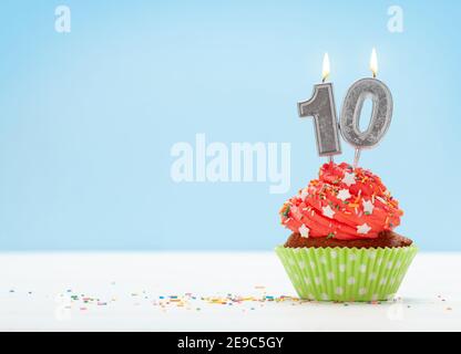 Compleanno cupcake con numero dieci candela bruciante su sfondo blu con spazio per la copia dei messaggi di saluto Foto Stock