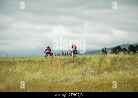 Ciclisti che percorrono il Central Rail Trail di Otago sotto il cielo nuvoloso verso Middlemarch, South Island, Nuova Zelanda Foto Stock