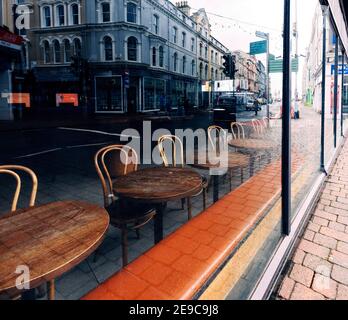Posti a sedere vuoti in una filiale chiusa del caffè Starbucks in Victoria Street, Douglas, Isle of Man con riflessi della strada nelle finestre Foto Stock