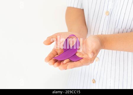 Mani che tengono il nastro viola o viola su sfondo bianco, spazio di copia. Cancro pancreatico, consapevolezza del cancro testicolare, sopravvivenza del cancro, Leiomiosarcoma Foto Stock