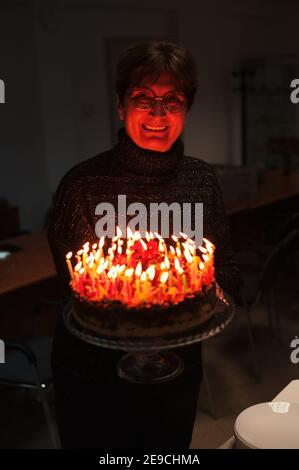 Ritratto di donna anziana che tiene torta di compleanno con candele Foto Stock