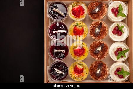 Scatola per la consegna del cibo per la cena. Consegna di cibo da mercati e ristoranti. Pasto per una settimana in quarantena. Dessert freschi tiramisù, souffle, gelatina al Th Foto Stock