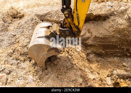 vista ravvicinata di un cucchiaio a artiglio dell'escavatore che scava trincea Foto Stock