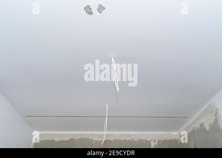 Due cavi provenienti dall'illuminazione dall'alto che sporgono dai soffitti senza lampadine. Foto Stock