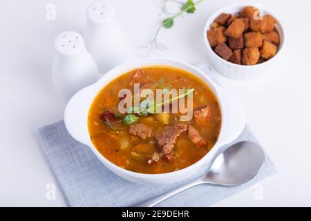 Zuppa di piselli con carne, salsiccia affumicata, germogli di piselli e crostini. Piatto tradizionale russo. Cucina domestica. Primo piano, messa a fuoco selettiva. Foto Stock