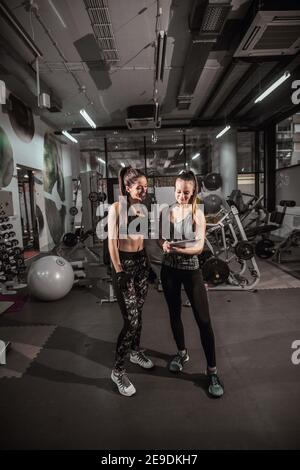 Trainer che mostra i risultati della formazione al suo cliente mentre si trova in palestra. Foto Stock