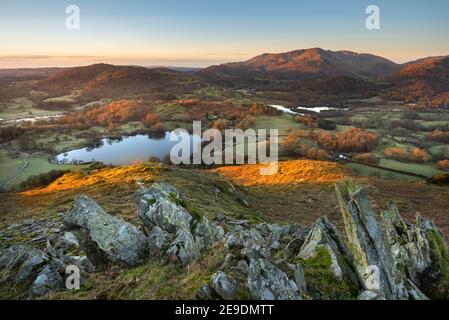 Splendida vista invernale della campagna inglese con sole di prima mattina sulle cime delle montagne. Loughrigg Fell, Lake District, Regno Unito. Foto Stock