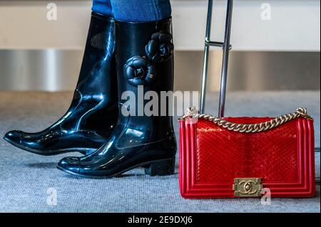 Londra, Regno Unito. 4 Feb 2021. Stivali Wellington designer di Chanel con design Camellia (parte di un set di 2 paia) est £200-300 con una Red Python Medium Boy Bag, Chanel, c.. 2014, est £2,000 - 3,000 - Preview of Bonhams' The Chanel Collection: Asta online dedicata alla lussuosa casa di moda francese e che offre più di 200 pezzi che vanno da abbigliamento e accessori a borse e gioielli a Bonhams Knightsbridge. La vendita sarà un'asta in linea temporizzata in corso per 11 giorni dal 5 al 16 febbraio compreso. Credit: Guy Bell/Alamy Live News Foto Stock