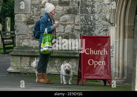 PUTNEY LONDON, REGNO UNITO. 4 Feb 2021. Una donna si trova con i suoi cani all'ingresso della Chiesa Parrocchiale di Fulham. Molte chiese stanno eseguendo la massa virtuale e non consentendo congregazioni a causa delle restrizioni del coronavirus. Credit: amer Ghazzal/Alamy Live News Foto Stock