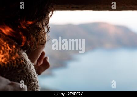 Primo piano di una donna irriconoscibile con un'ascolto riccamente piacevole una vista del tramonto durante il viaggio Foto Stock